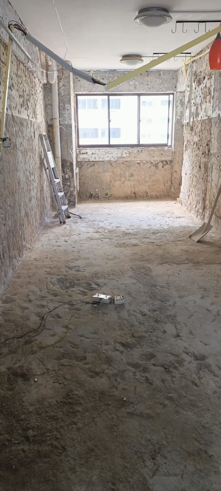Stripped bare site with exposed walls and window before JBC demo works