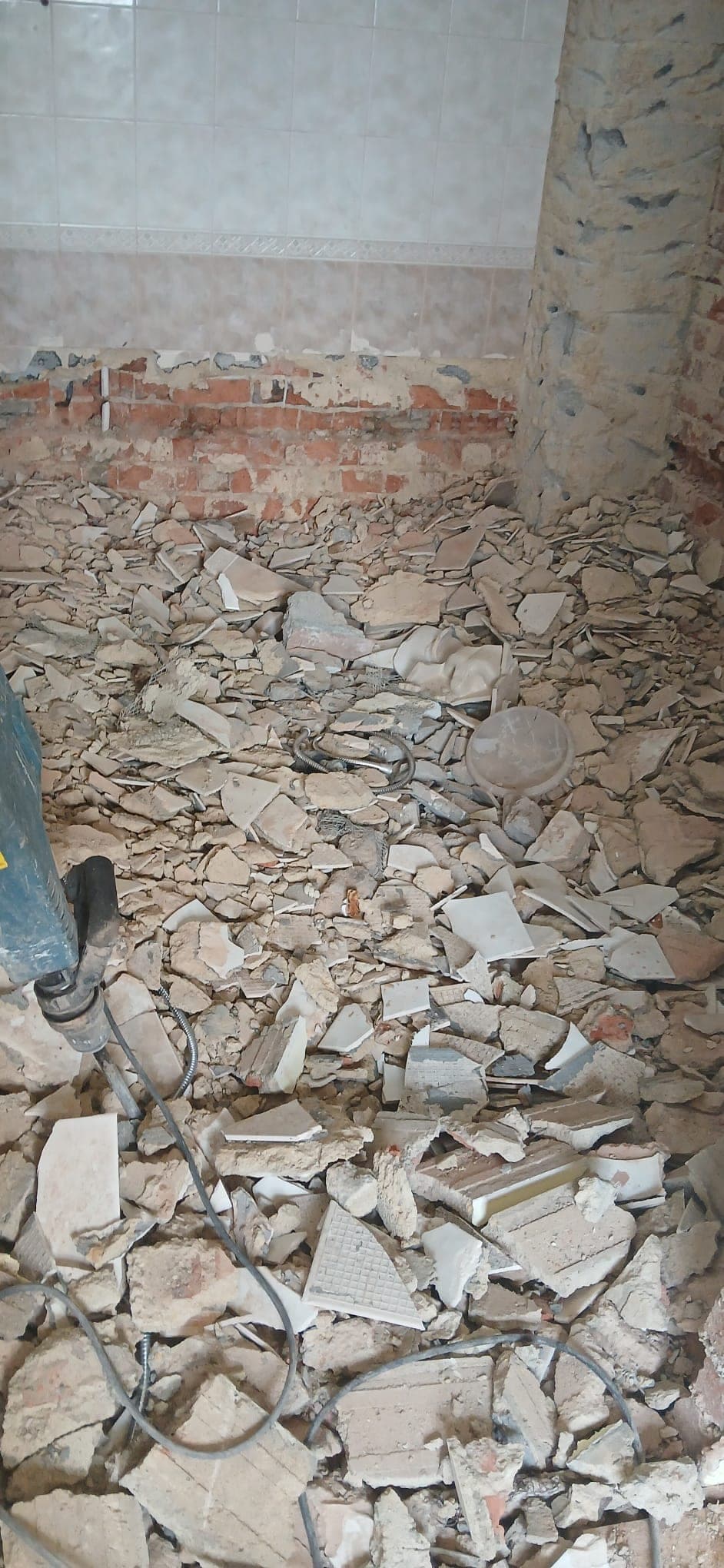 Broken tiles and debris in wet area after hacking works